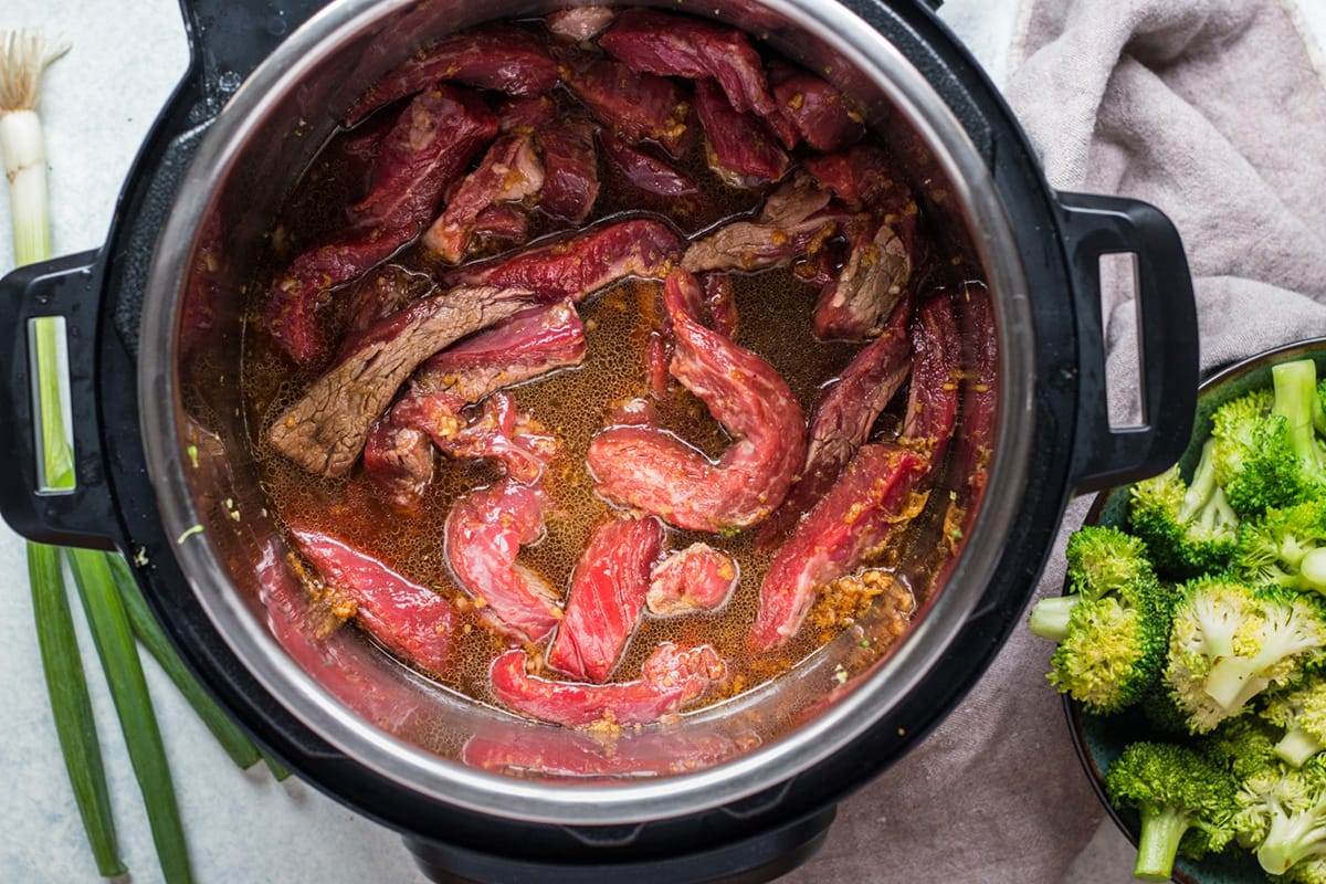 Beef cooking in an Instant Pot to make a beef and broccoli dish.