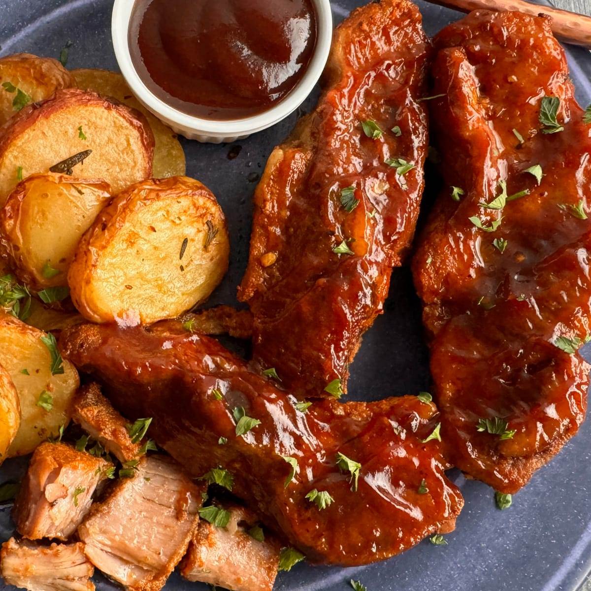 Country-style pork ribs served with potatoes and BBQ sauce.