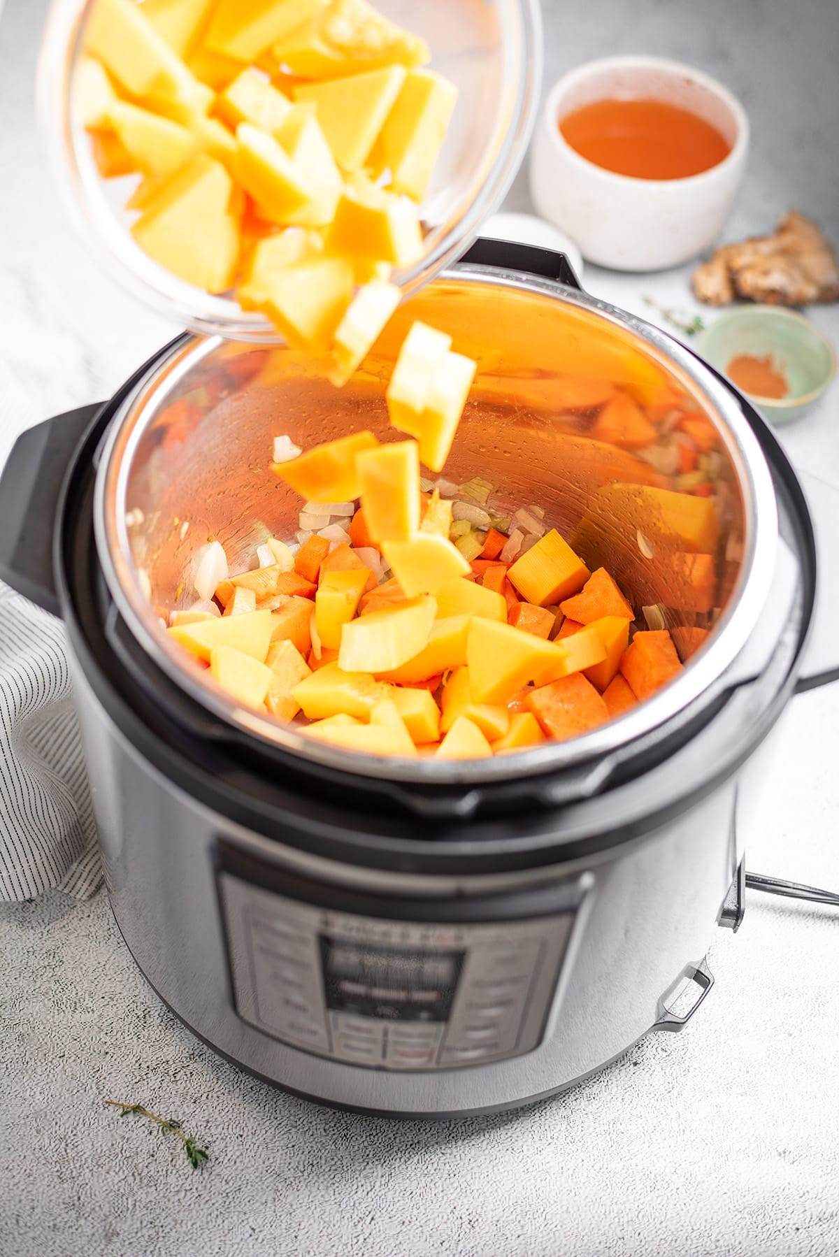 Adding the ingredients to the Instant Pot to make butternut squash and sweet potato soup.