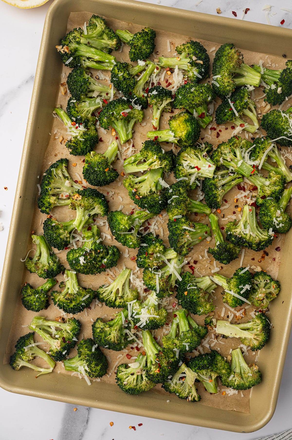 Oven roasted broccoli on a sheet pan with fresh Parmesan cheese.