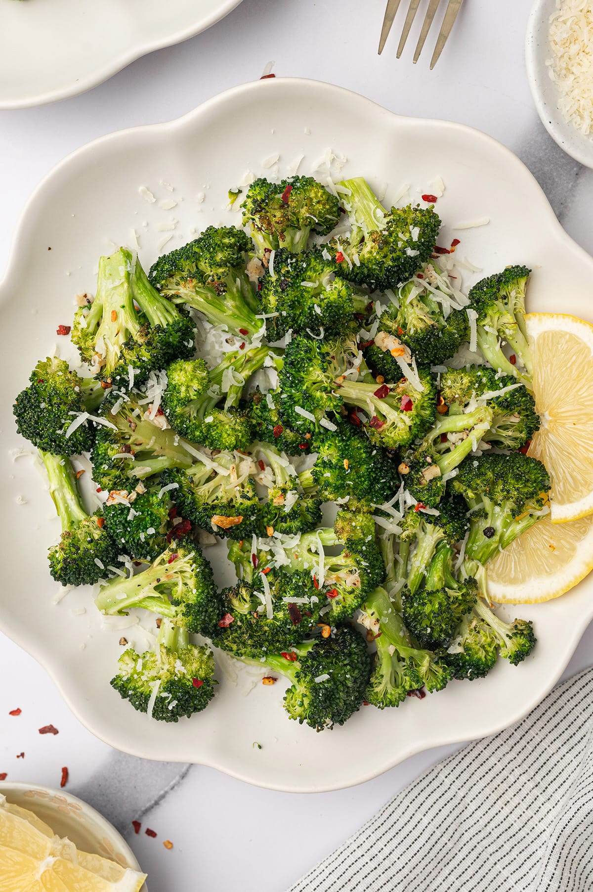Oven roasted garlic parmesan broccoli served in a bowl with lemon slices.