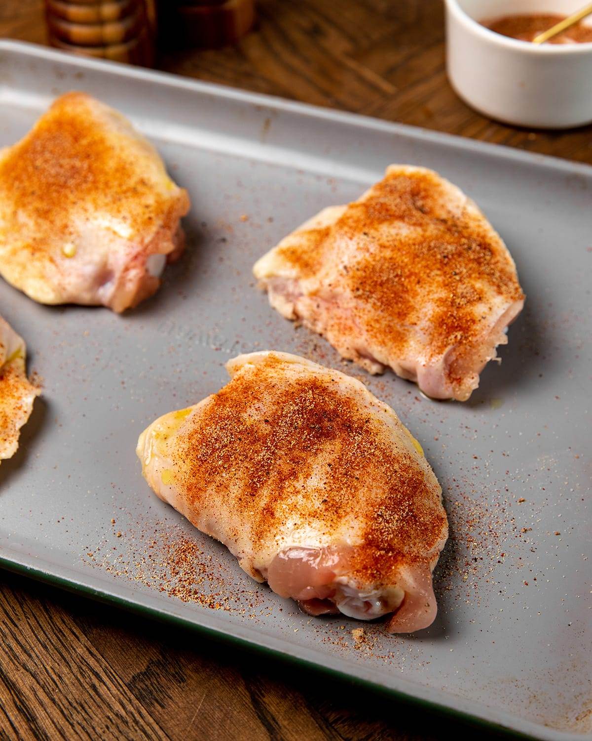 Seasoned chicken thighs on a sheet pan.
