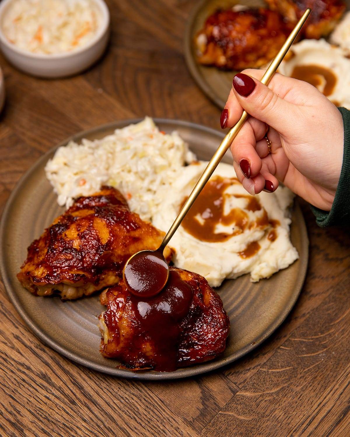 Oven roasted BBQ chicken thighs with mashed potatoes, cole slaw and additional BBQ sauce.