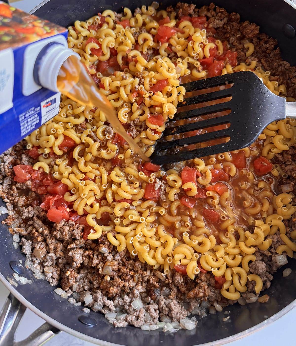 Adding all the ingredients to make skillet taco pasta!