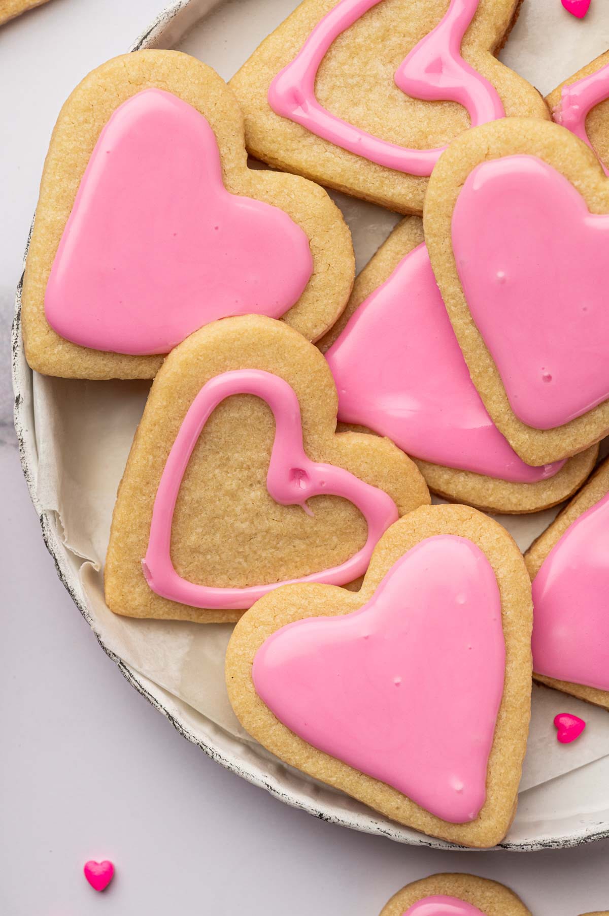 Close-up image of heart-shaped sugar cookies on a white plate.
