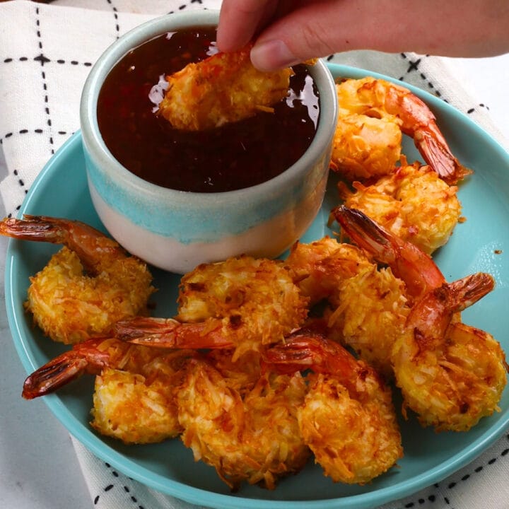 A plate of coconut shrimp made in an air fryer and served with a dipping sauce.