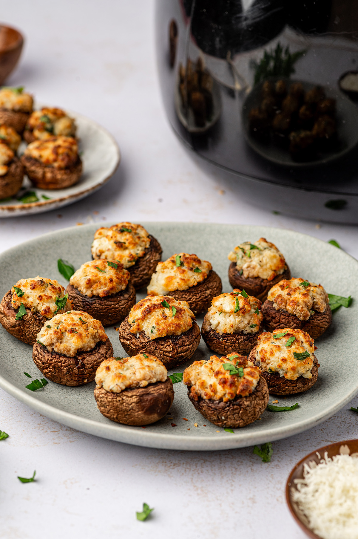 Air fryer stuffed mushrooms on a teal plate with garnish.
