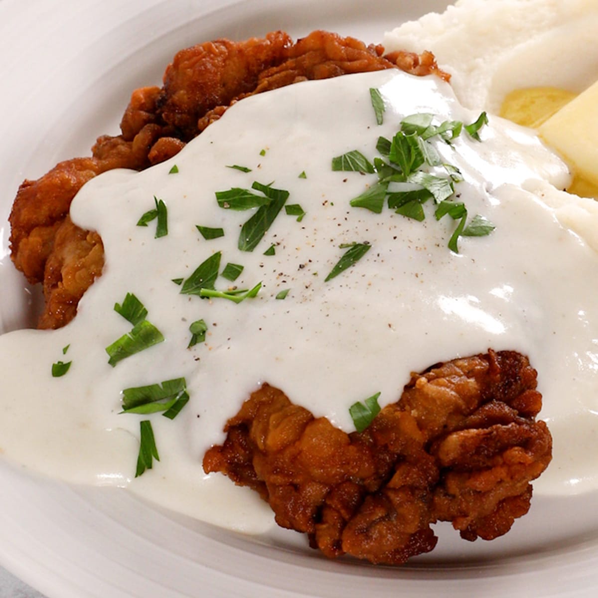 Close up of country fried steak on a white plate.