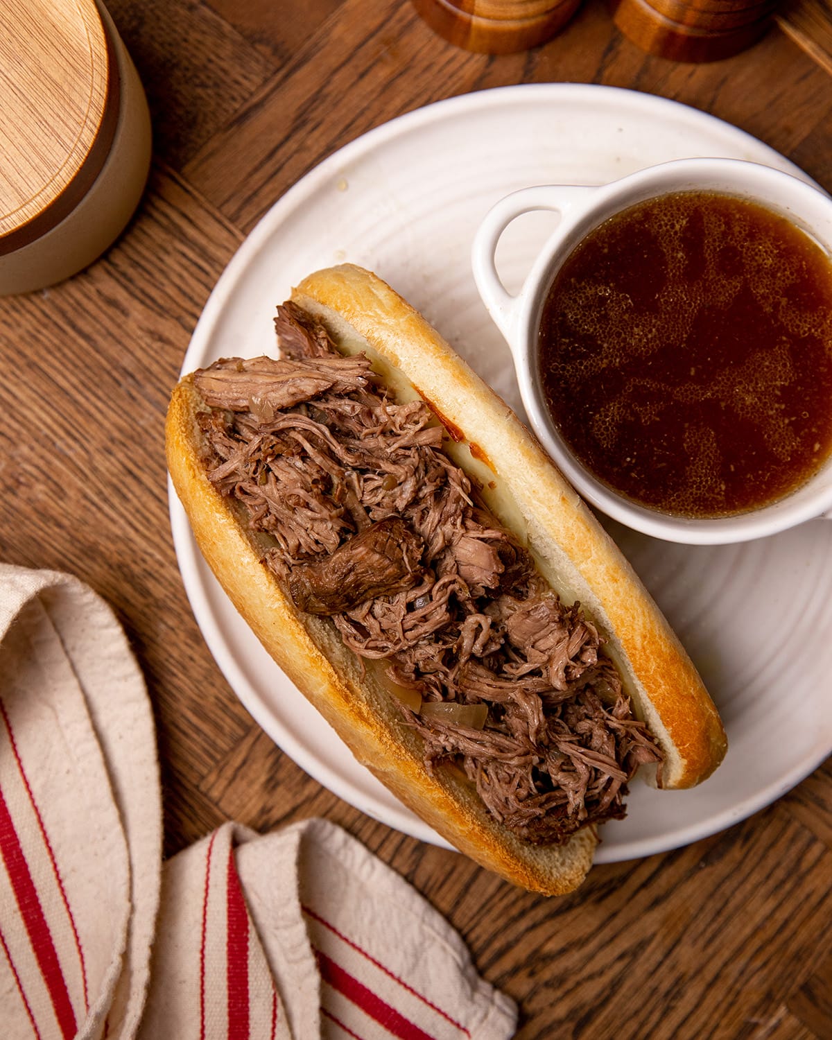 A serving of slow cooker French dip sandwiches on a white plate with au jus.