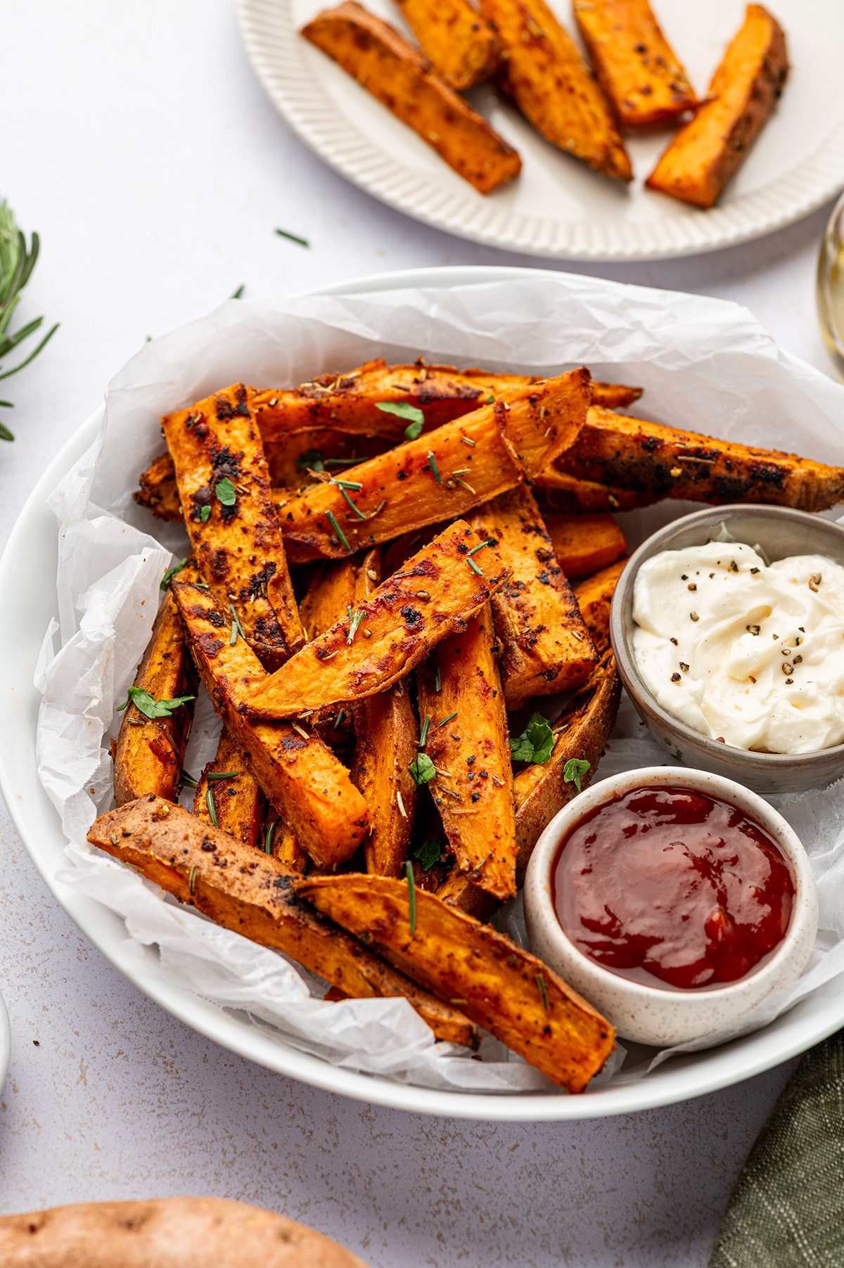 Roasted sweet potato wedges on a white plate with dipping sauce.