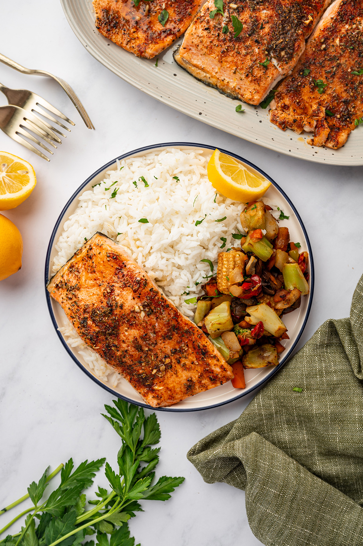 Garlic butter salmon on a plate with rice and vegetables.