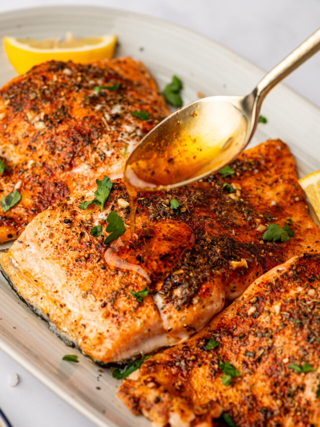 Pouring garlic butter on cooked salmon fillets.