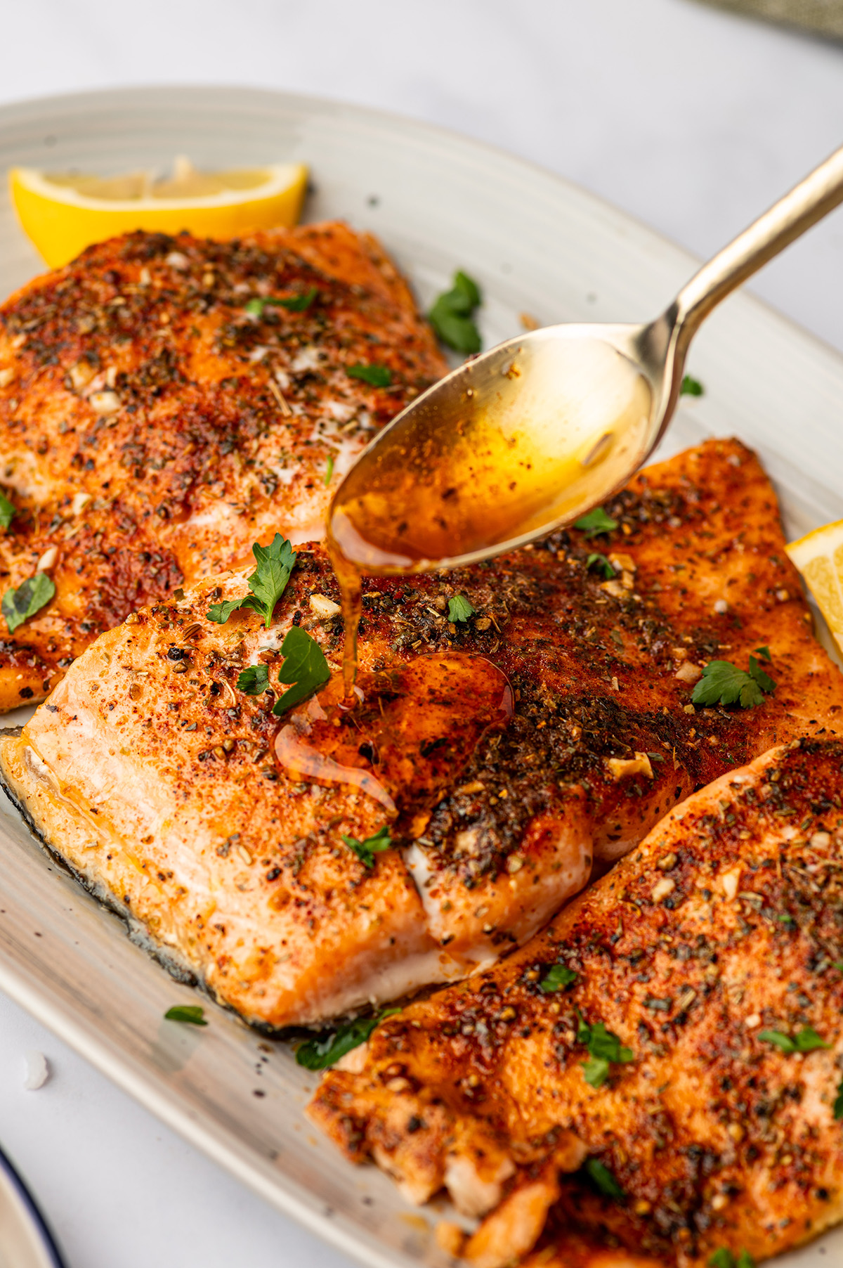 Pouring garlic butter on cooked salmon fillets.