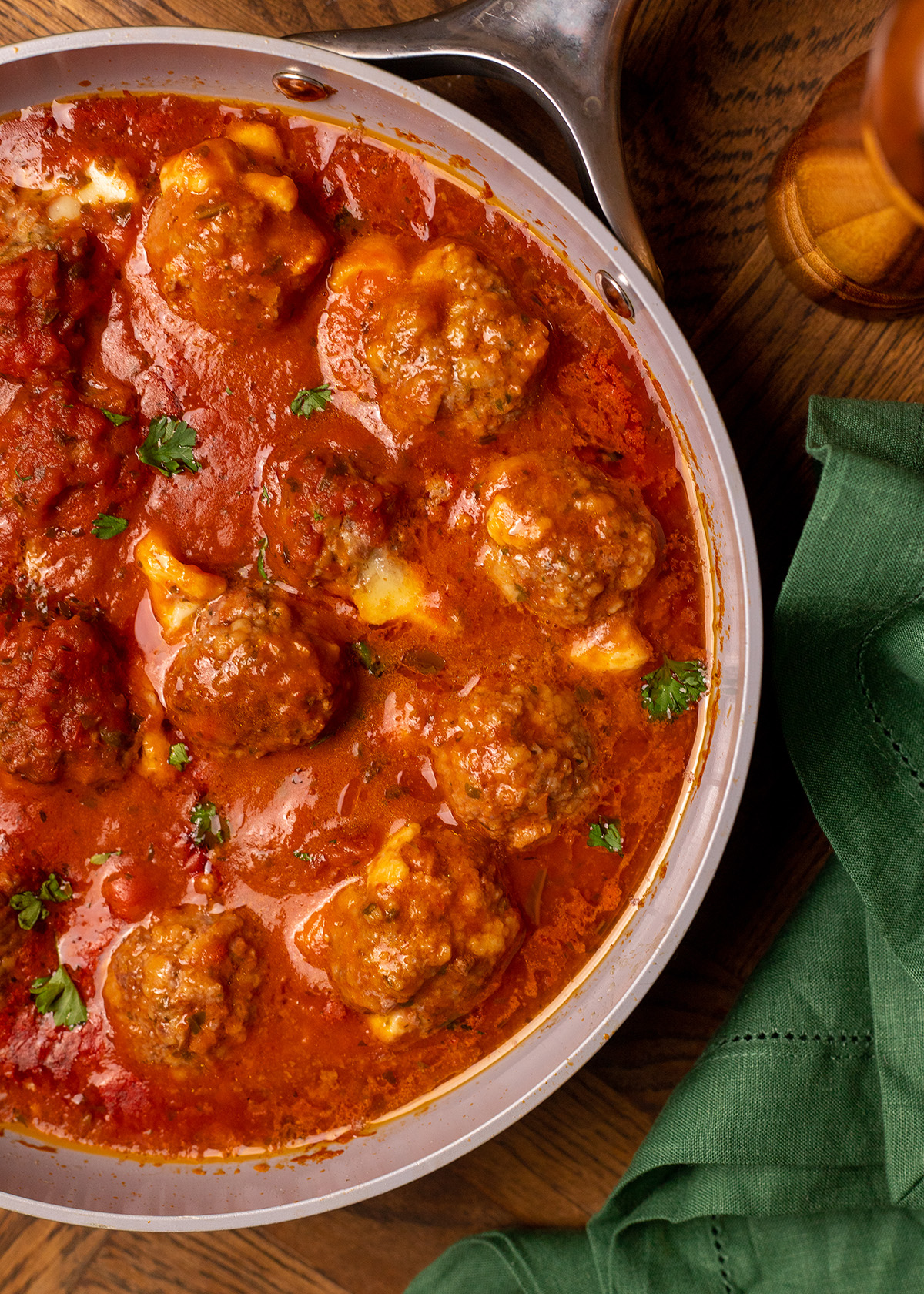 Cheesy stuffed meatballs simmering in a skillet with marinara sauce.