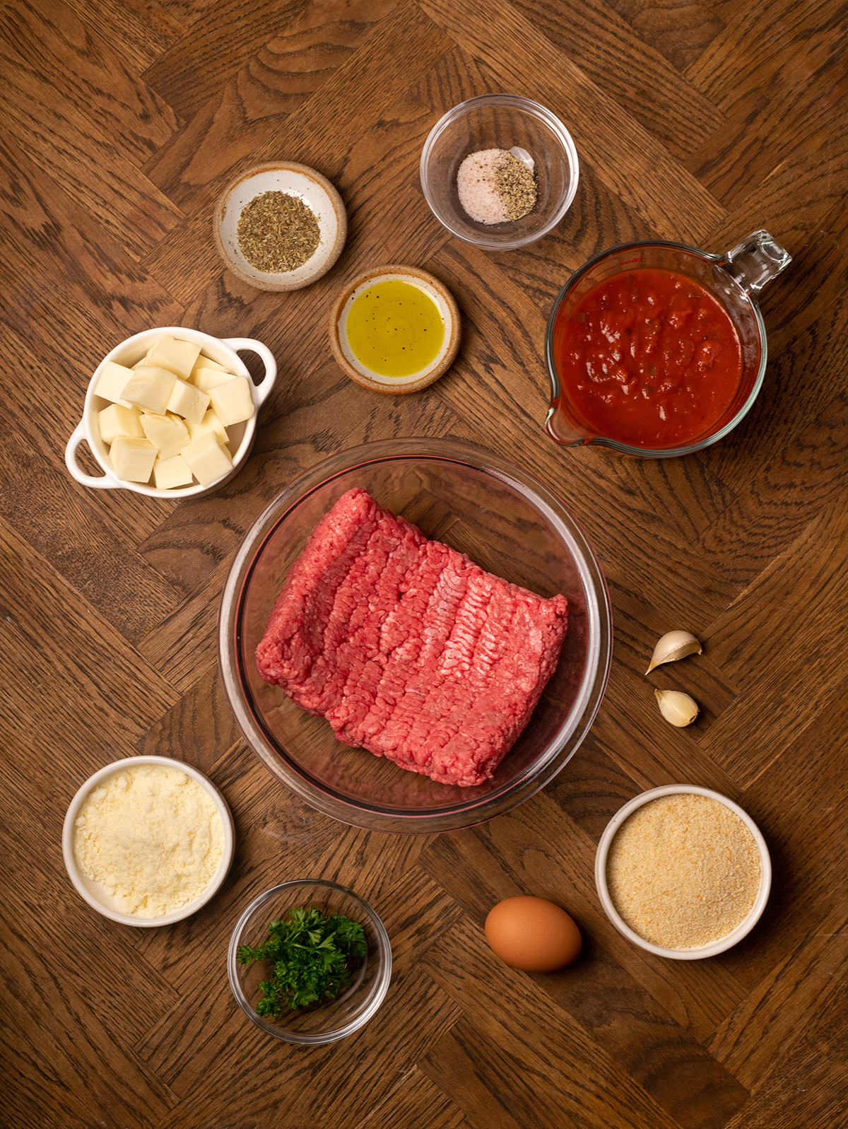 Ingredients for stuffed meatballs spread out over a wooden surface.
