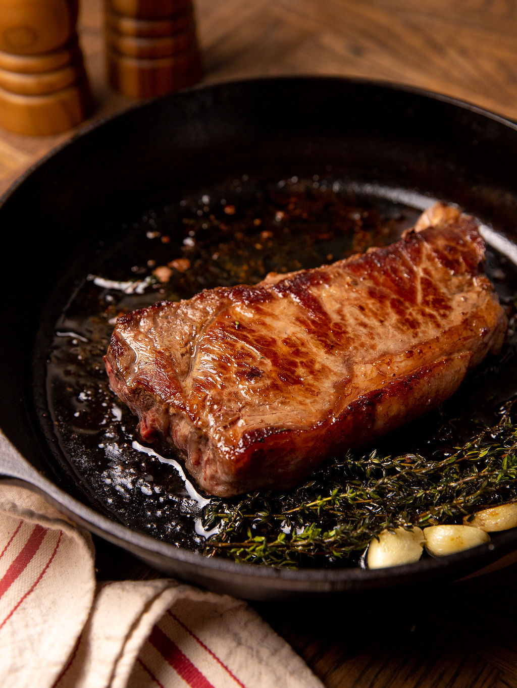 A juicy steak cooking in a cast iron pan with butter and garlic.