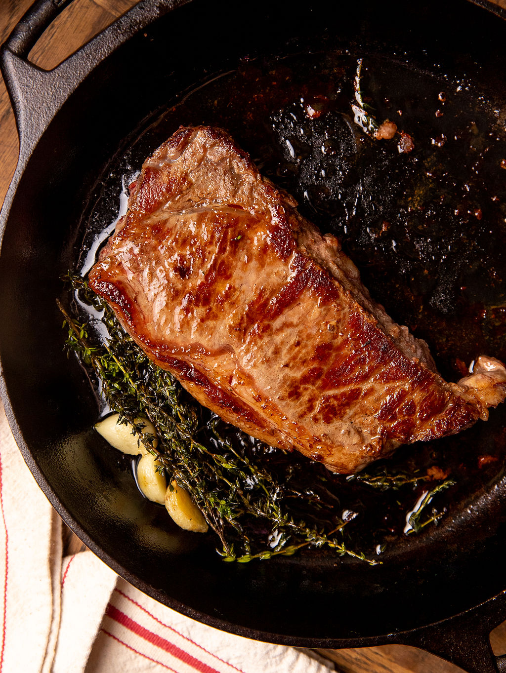 Cooking a steak in a cast iron skillet with butter and garlic.