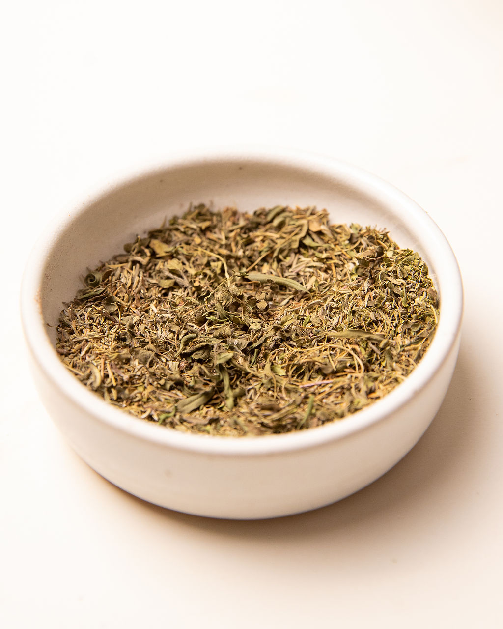 A white bowl of dried herbs.