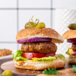 A stacked air fryer turkey burger with lettuce, tomato, onion, and pickle on top.