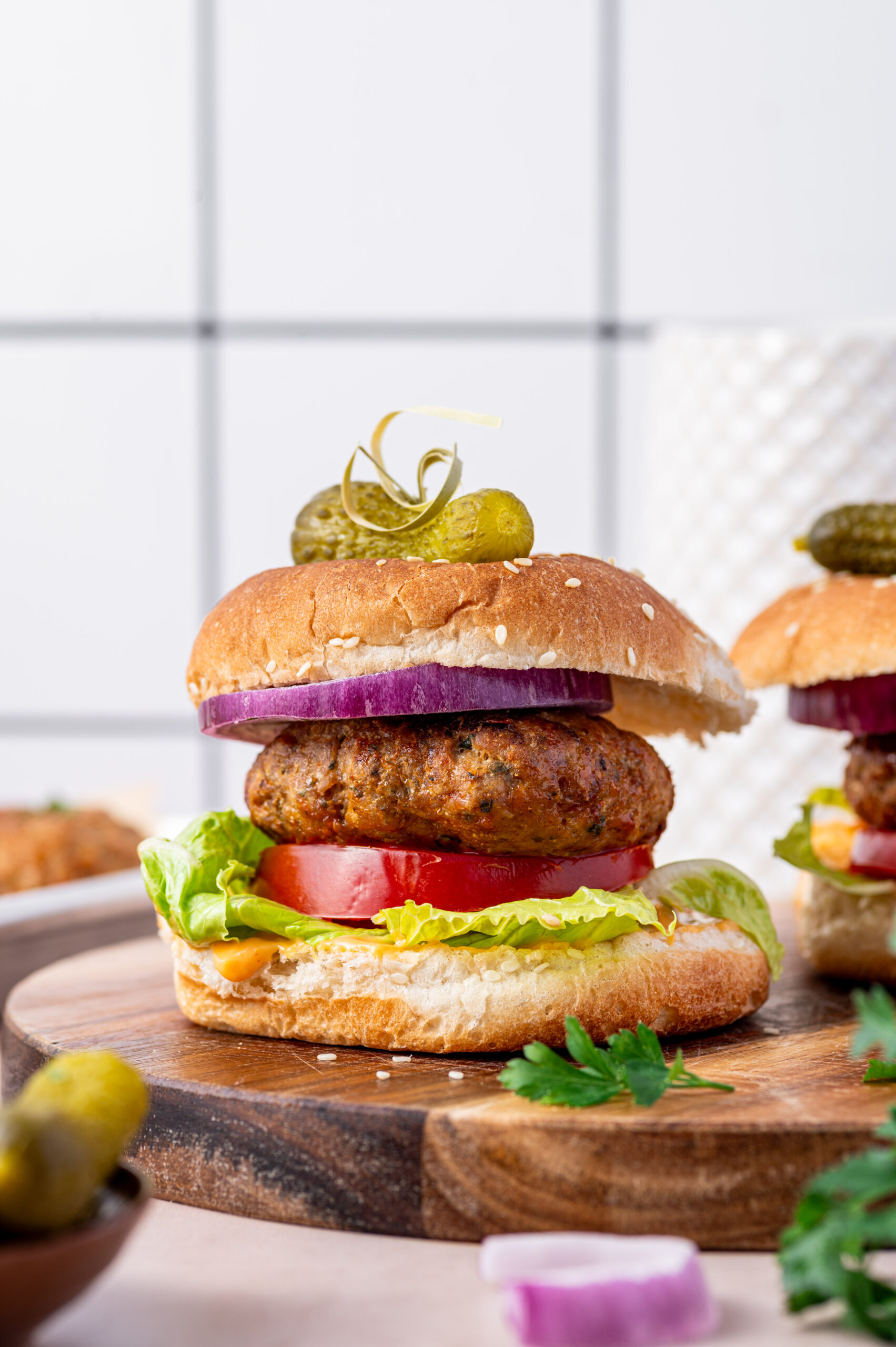 A stacked air fryer turkey burger with lettuce, tomato, onion, and pickle on top.