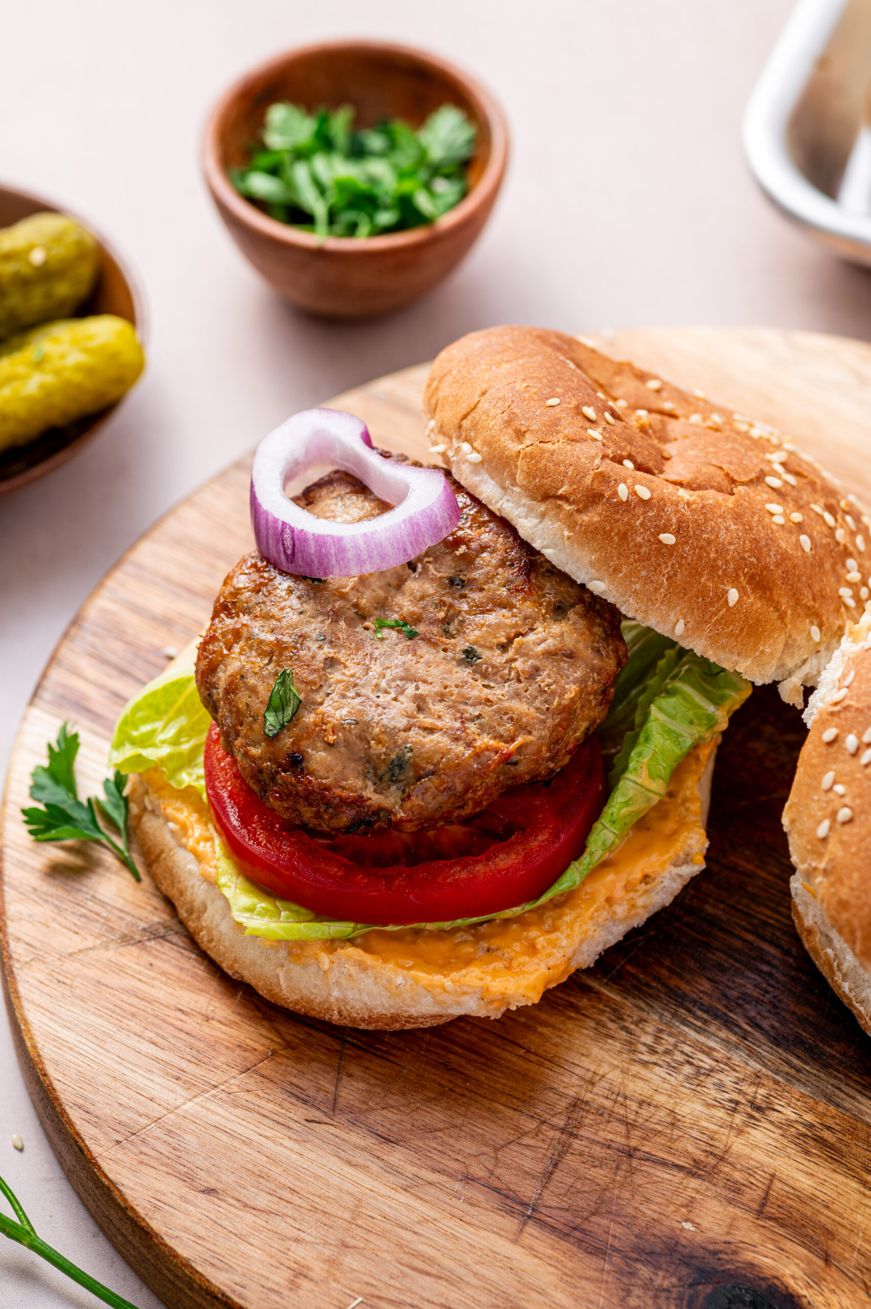 An open-faced air fryer turkey burger with onion, tomato, and lettuce on a wooden serving tray.