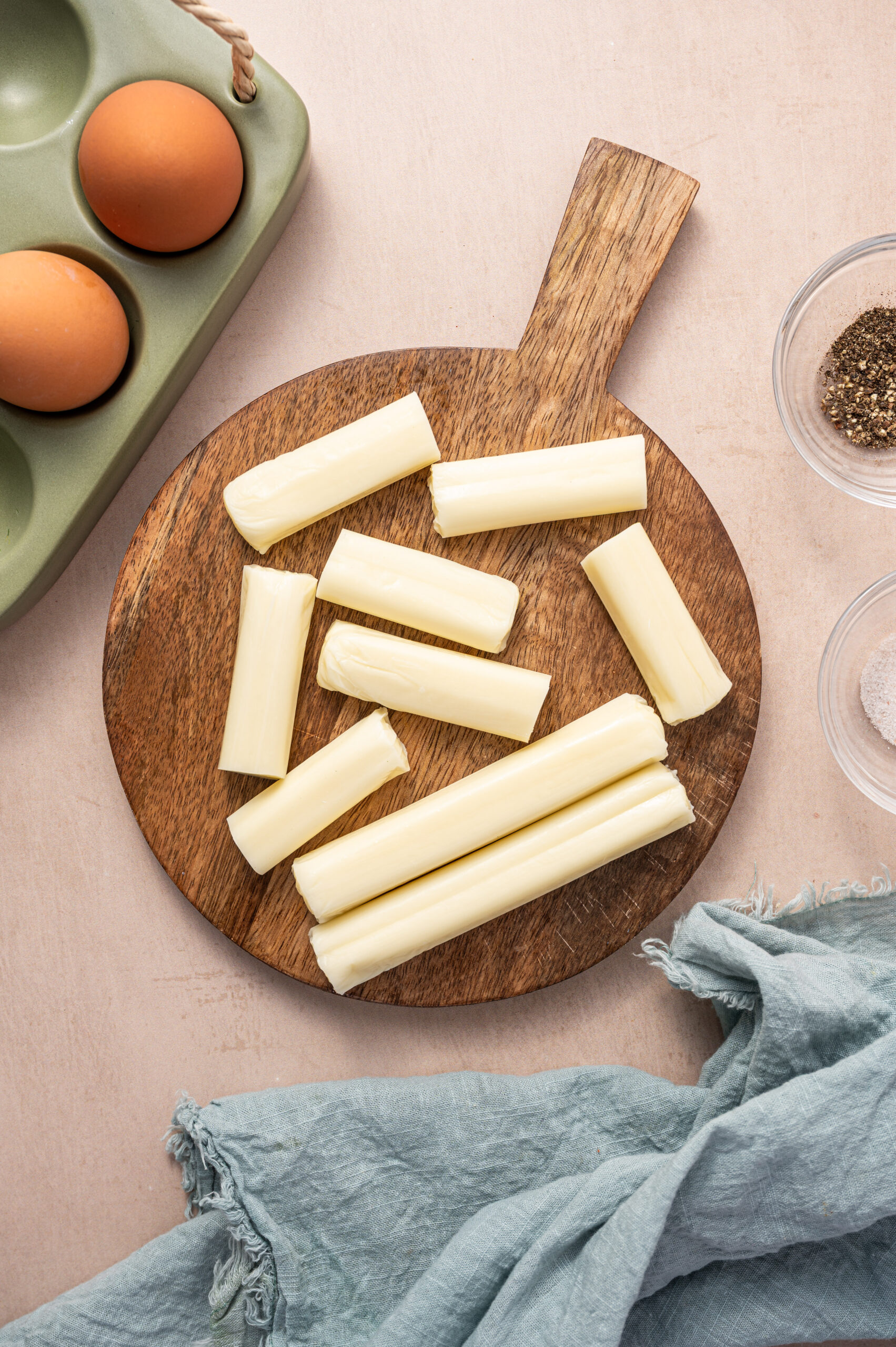 Mozzarella cheese sticks on a wooden cutting board.