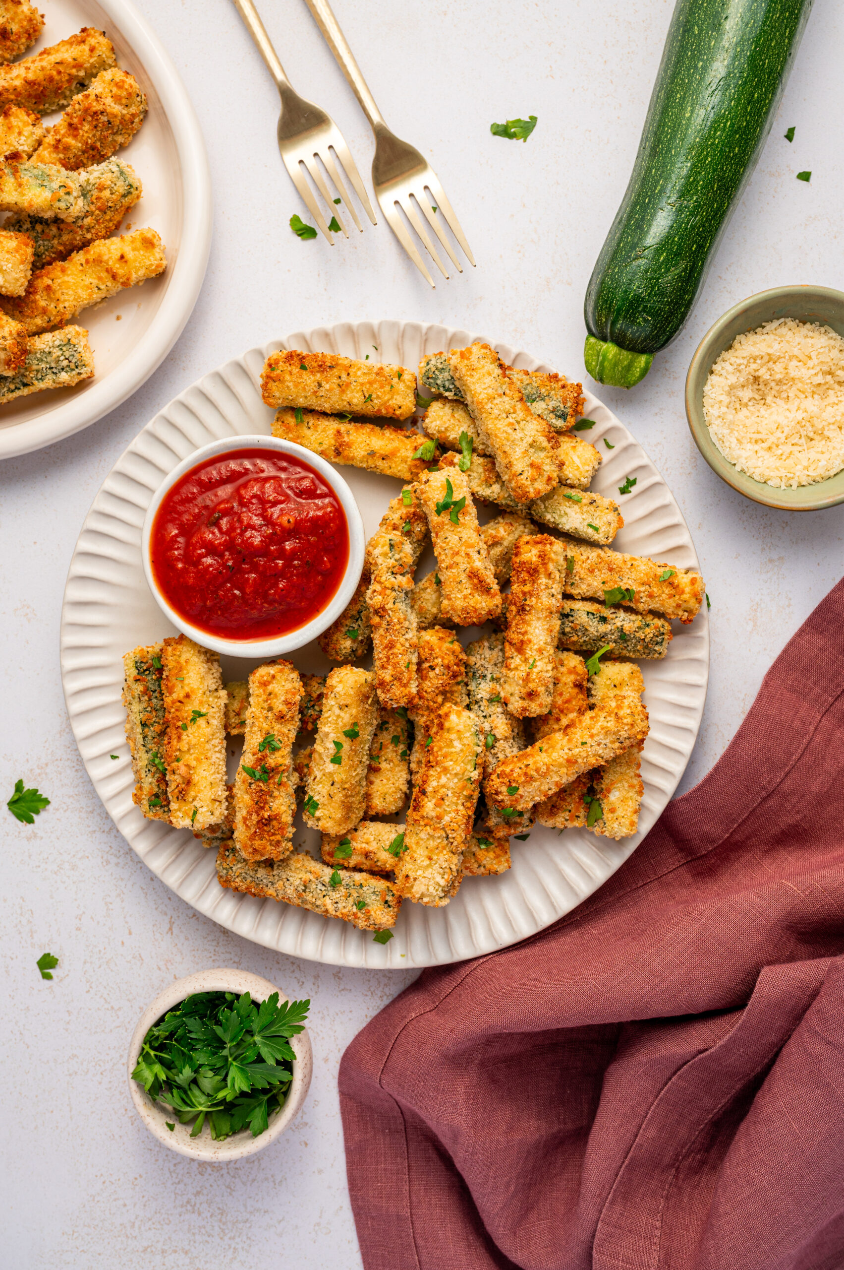 A serving of air fryer zucchini fries on a white plate with side of sauce.