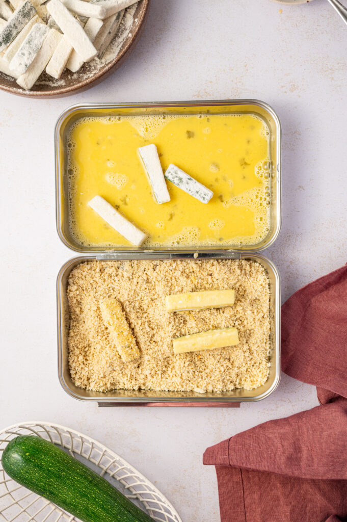 Dipping zucchini sticks in egg wash and breading.