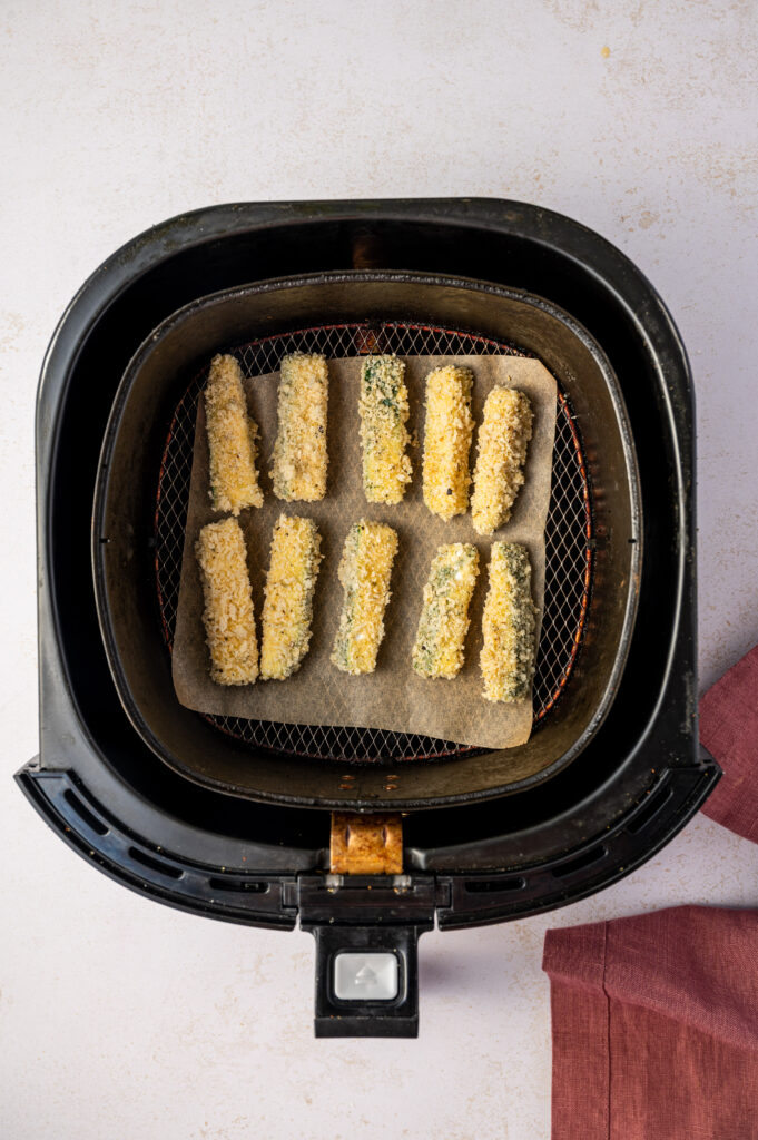 Air fryer zucchini fries in an air fryer basket before getting cooked.