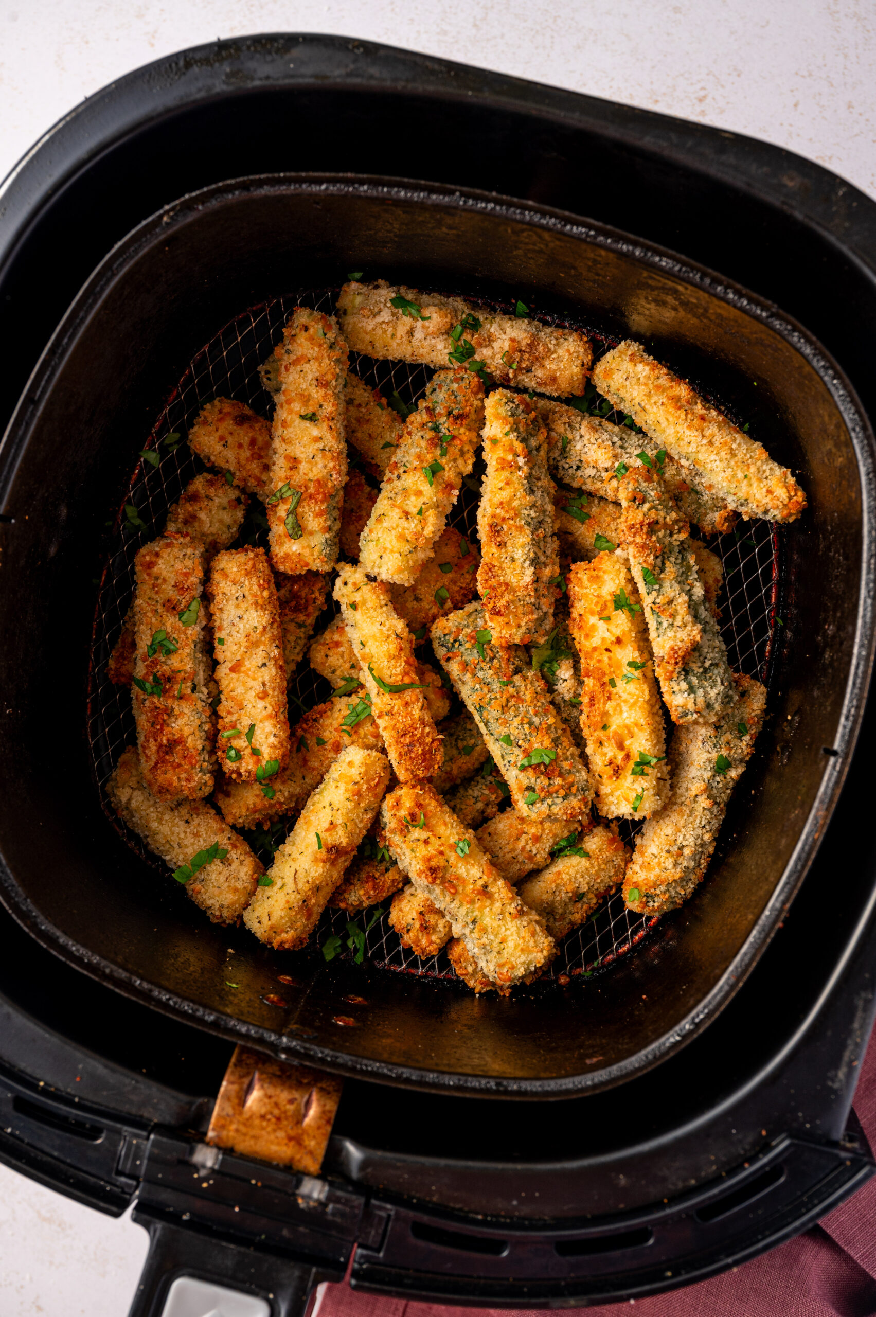 Air fryer zucchini fries in an air fryer basket.