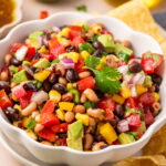 Colorful cowboy caviar in a white serving bowl.
