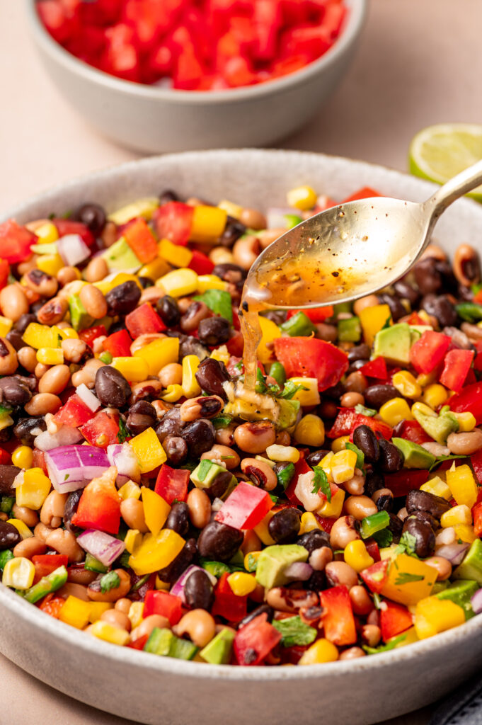 Pouring the dressing over the cowboy caviar with a silver spoon.