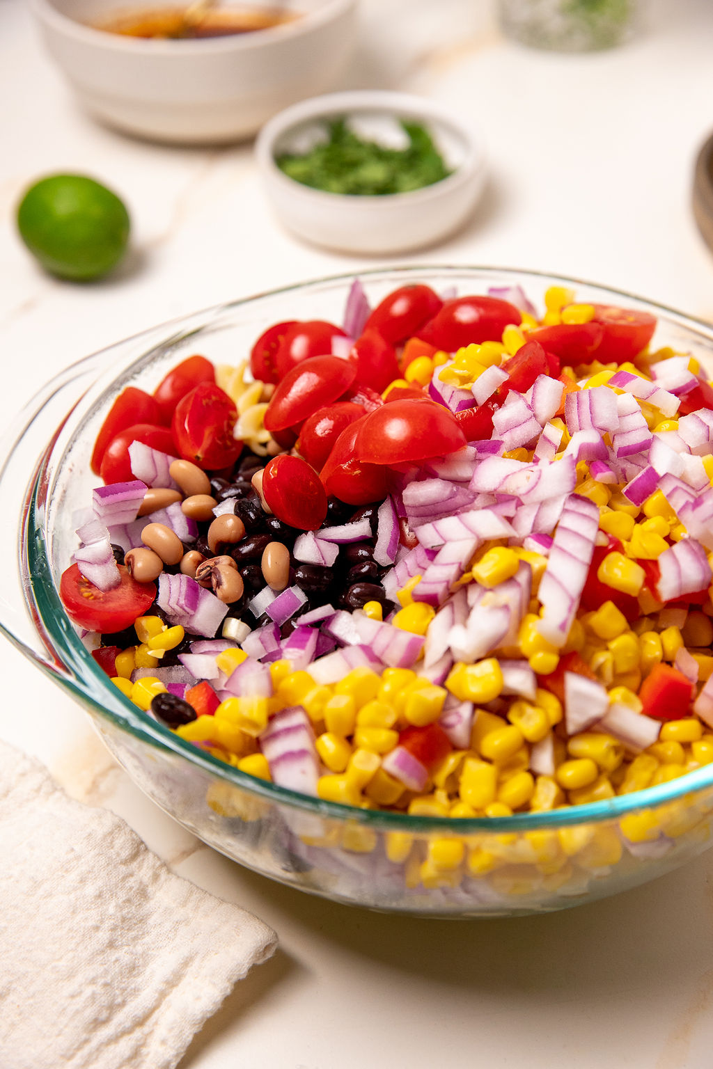 A glass bowl full of veggies for cowboy caviar pasta salad.