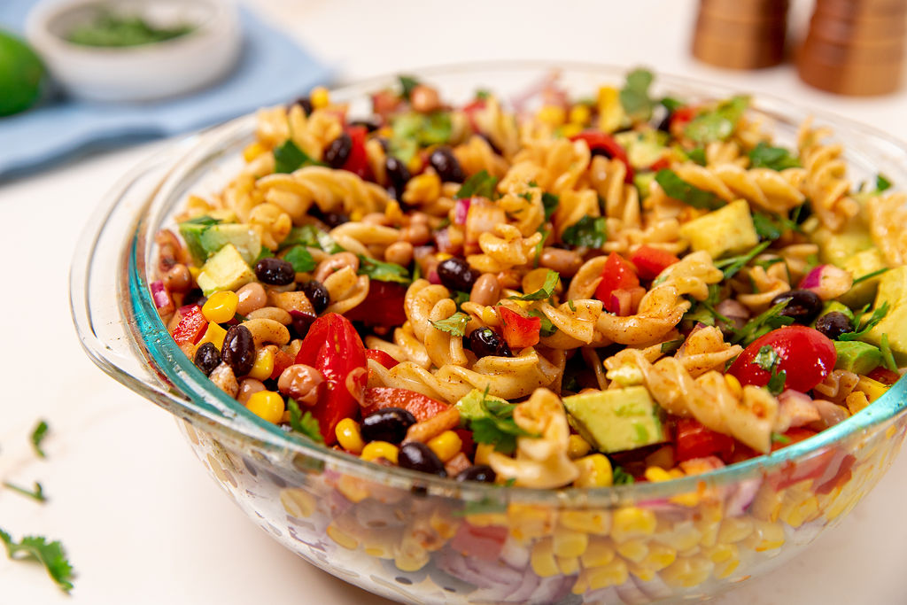 Cowboy caviar pasta salad in a glass serving bowl.