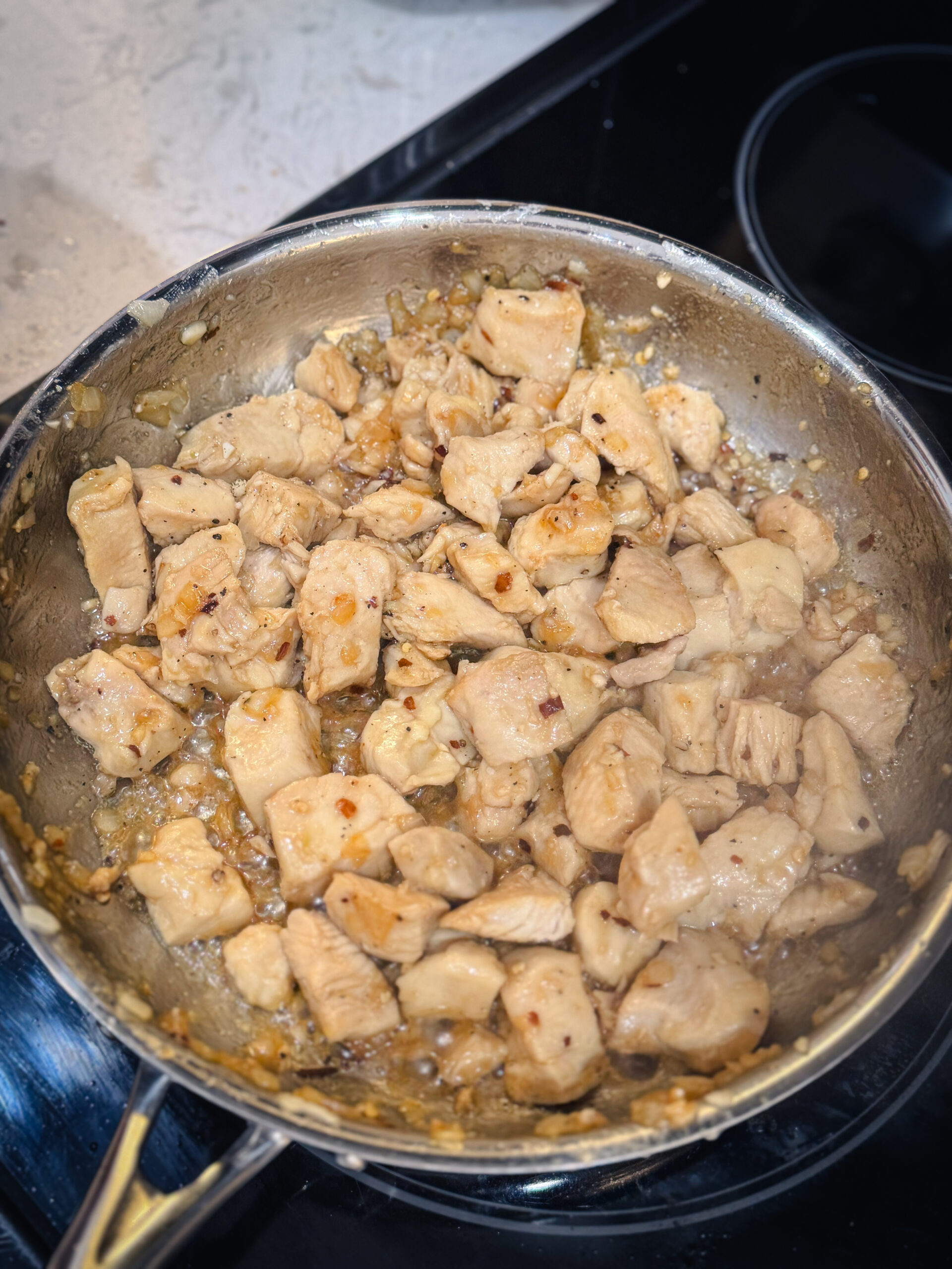 Chicken cooking in a skillet with spices.