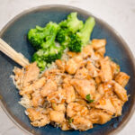 Honey garlic chicken on a blue plate with a side of broccoli.