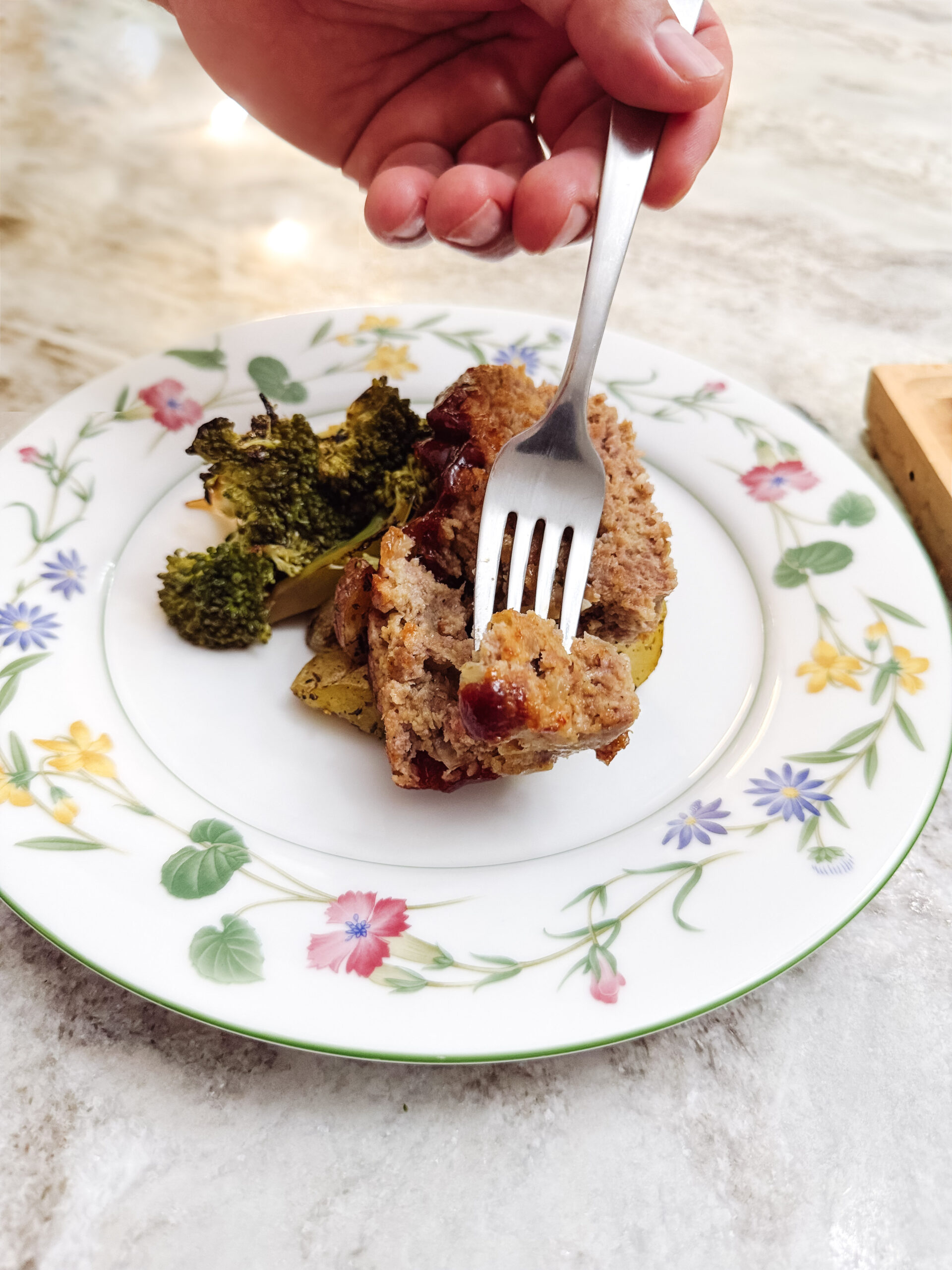 Dipping a fork into a serving of classic meatloaf on a plate.