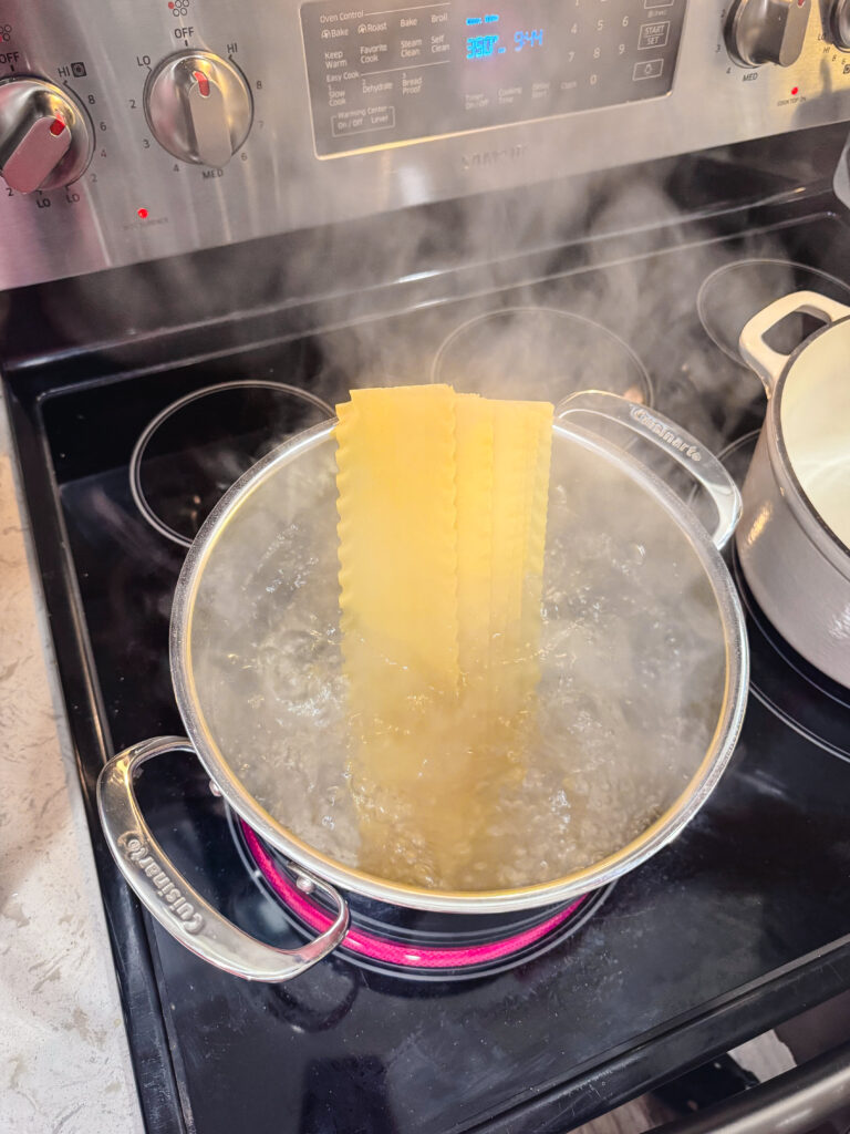 Cooking lasagna noodles in a boiling pot of water.