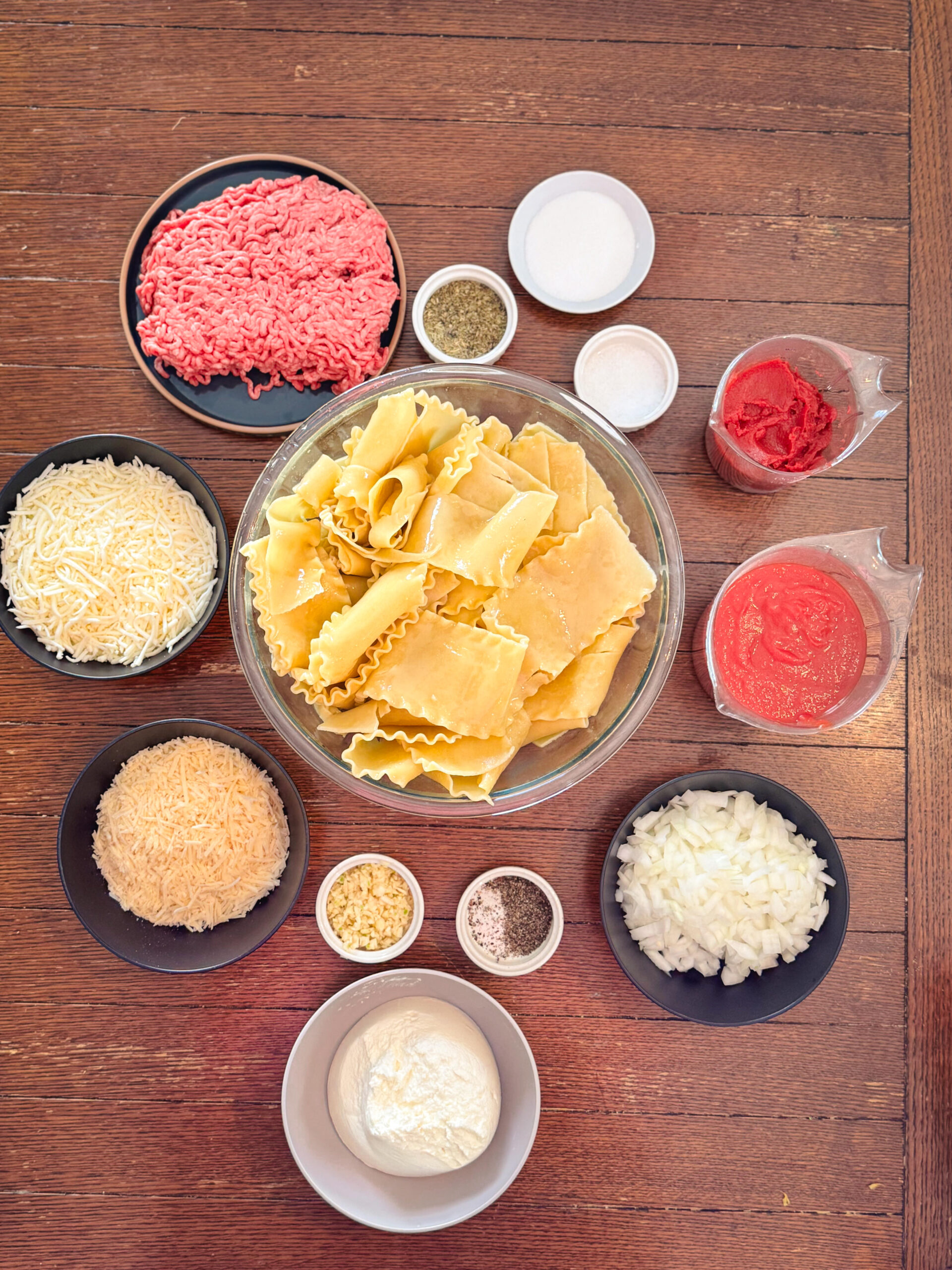 Ingredients for oven baked lasagna on a wooden table.