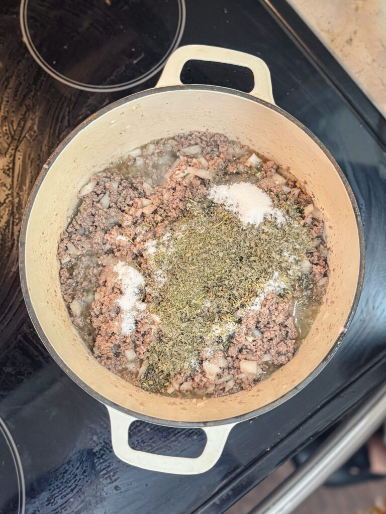 Ground beef browning in a Dutch oven with spices.