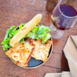 A serving of oven baked lasagna with a side salad and garlic bread.
