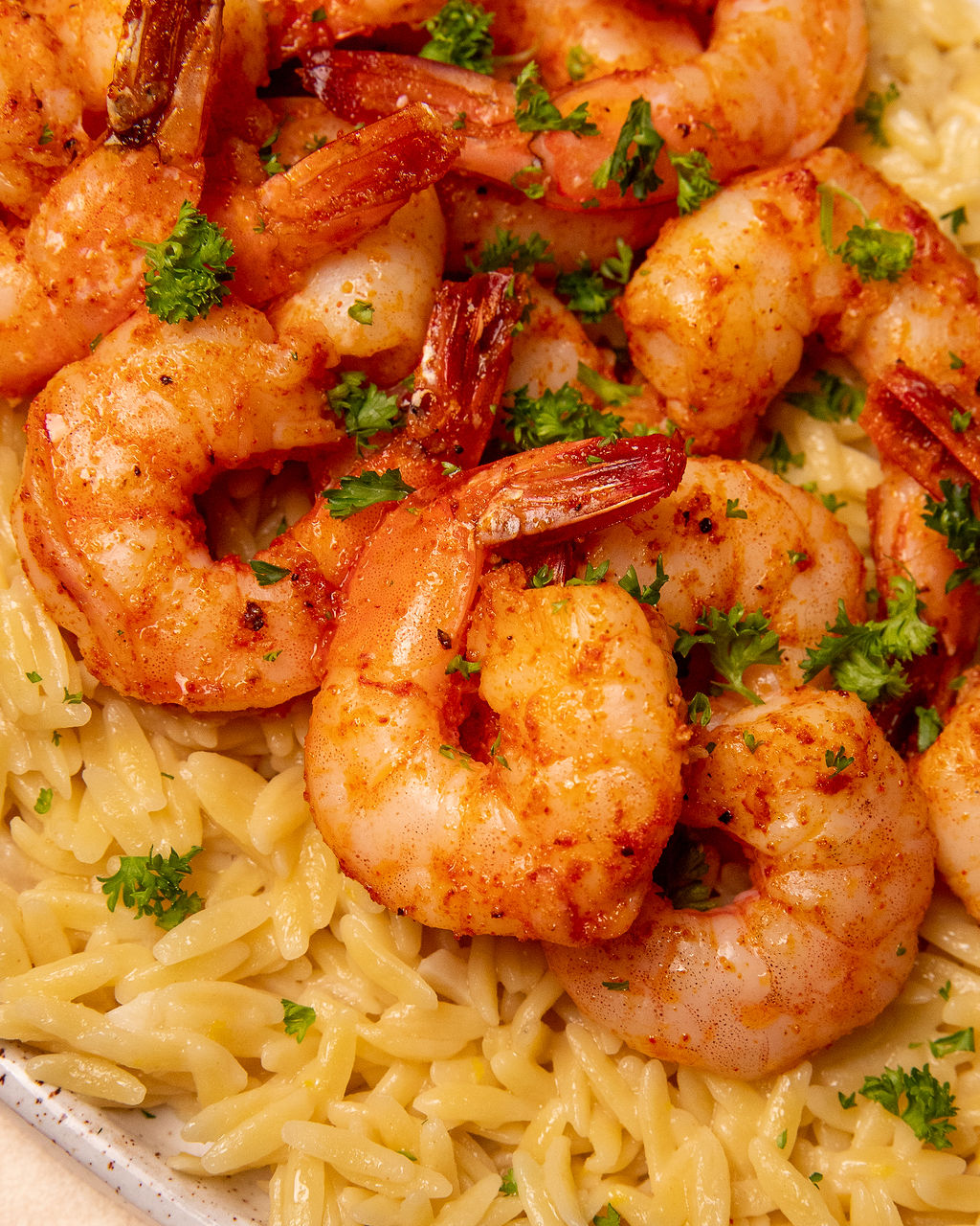 Close-up of roasted shrimp and orzo with fresh parsley.