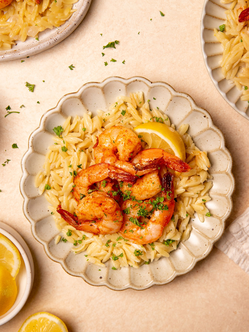 Roasted shrimp and orzo on a plate with a lemon wedge and garnish.