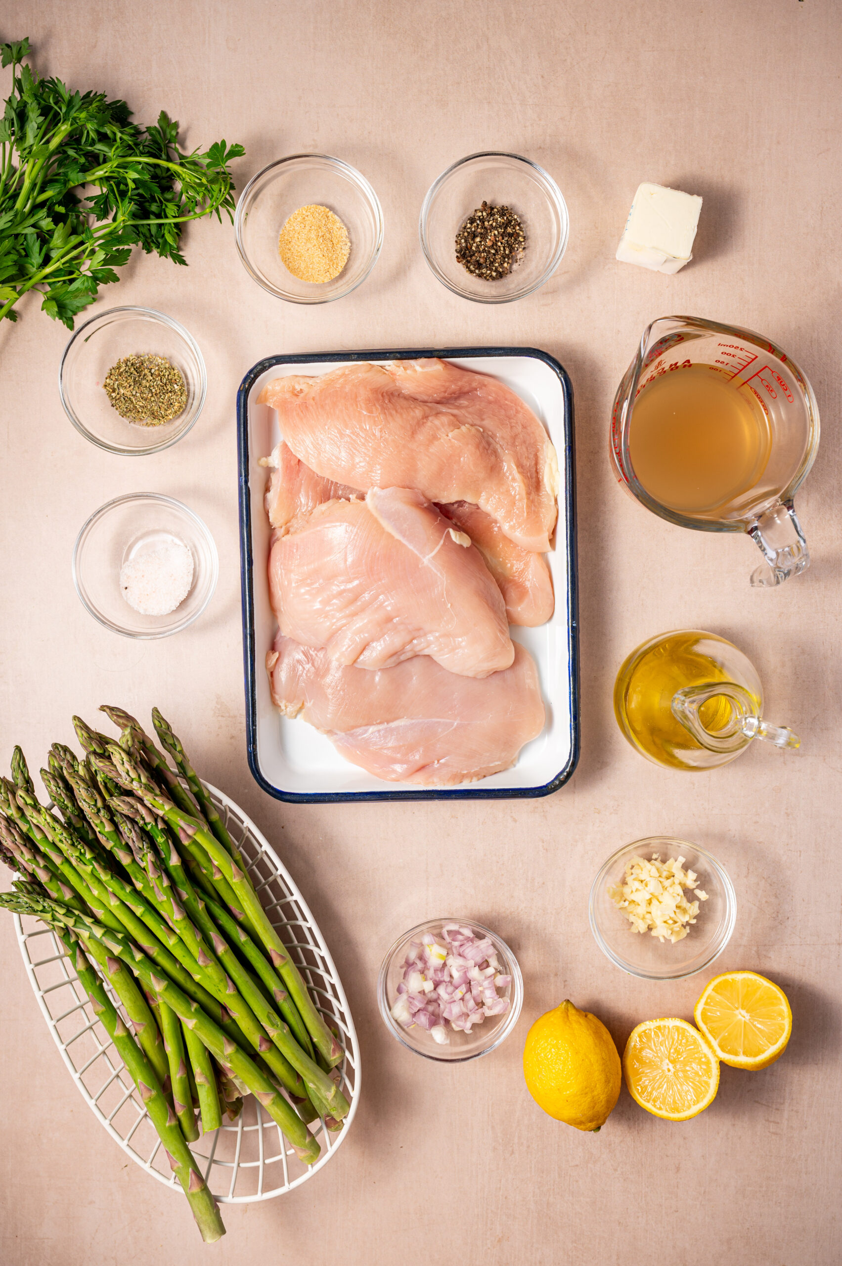 Ingredients for lemon herb chicken with asparagus on a counter top.
