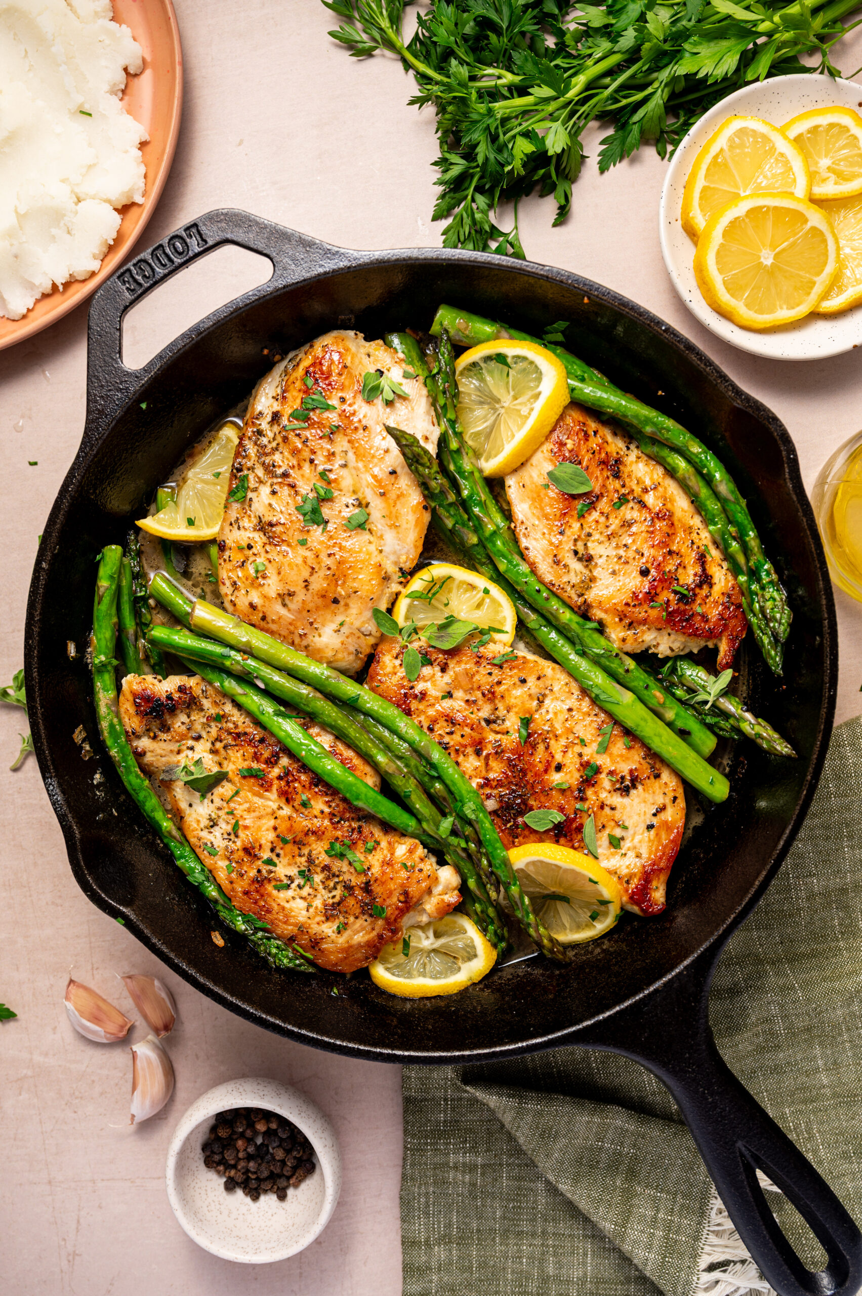 Lemon herb chicken with asparagus on a skillet ready to eat with lemon wedges as garnish.