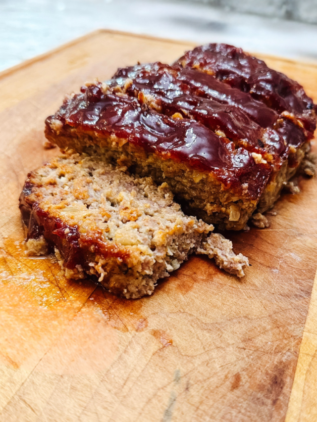 Classic meatloaf on a cutting board cut into slices.