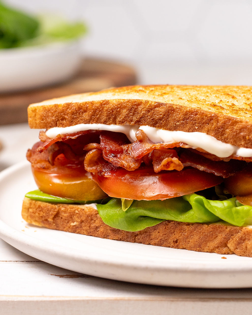 Close-up of a BLT sandwich with bacon, lettuce, tomato, mayo, and Dijon.