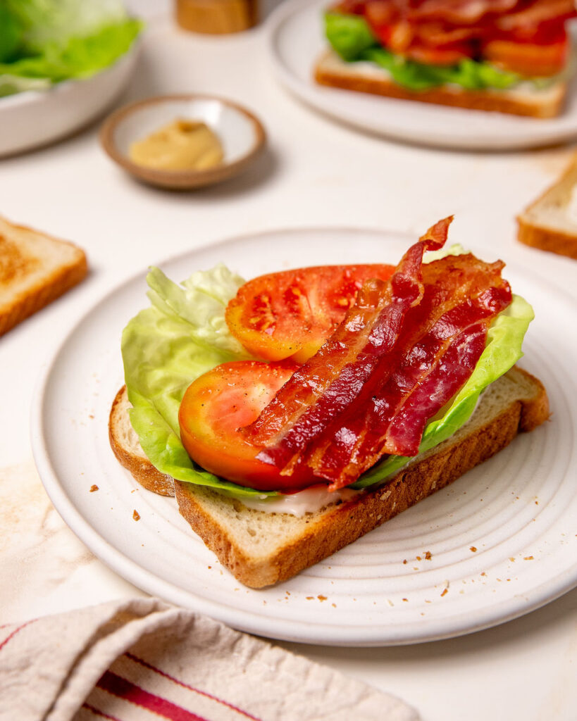 Adding lettuce, tomato, and bacon to a BLT sandwich.