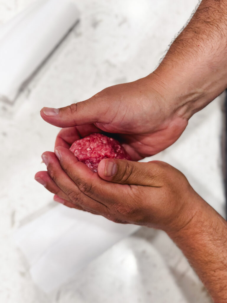 Rolling ground beef into balls to make smash burgers.