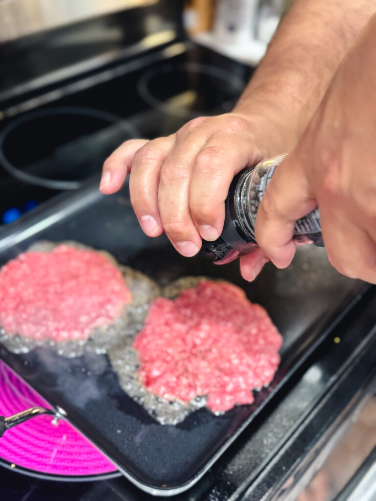 Seasoning smash burger patties with salt.